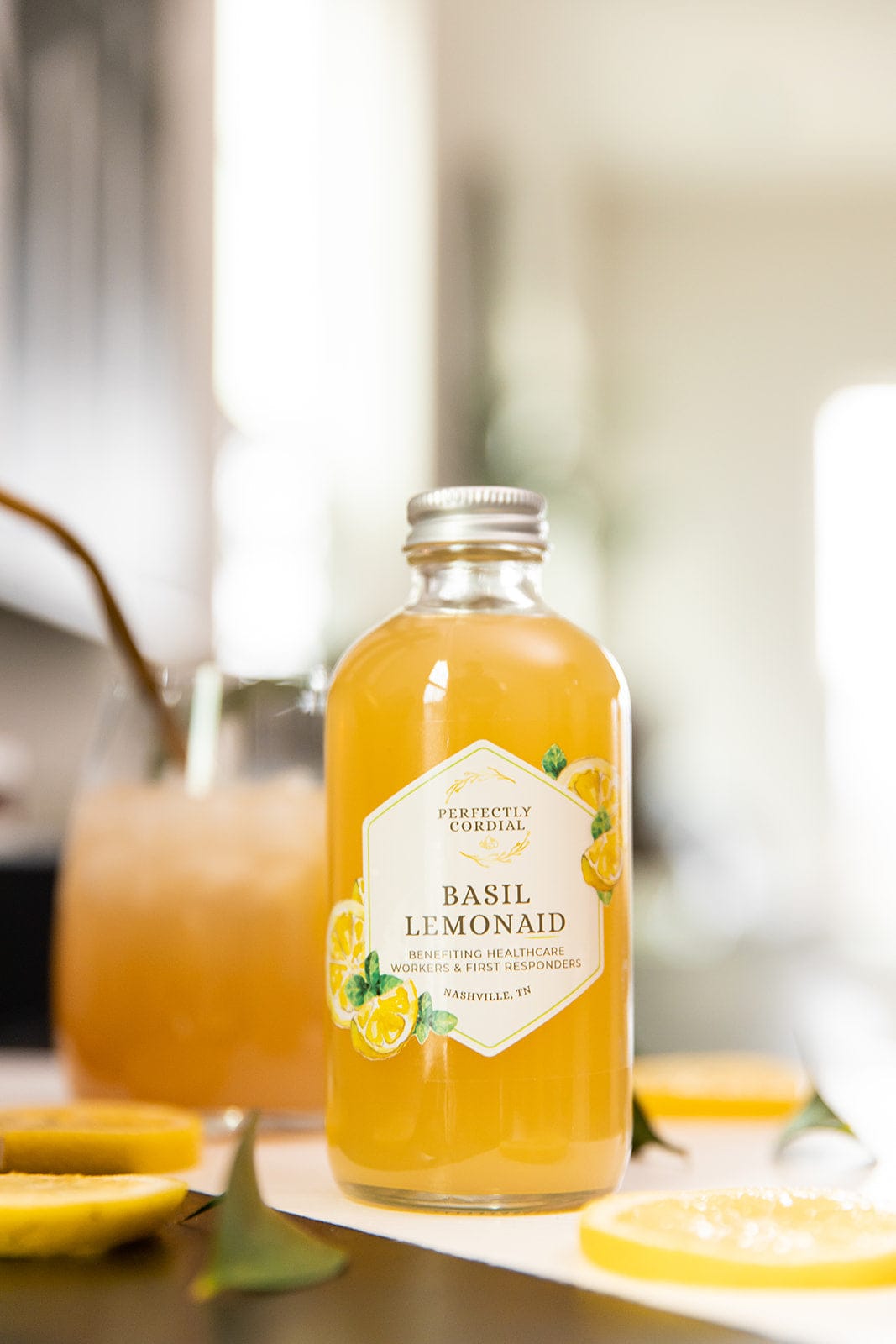 Basil LemonAid bottle on a kitchen counter beside an iced drink