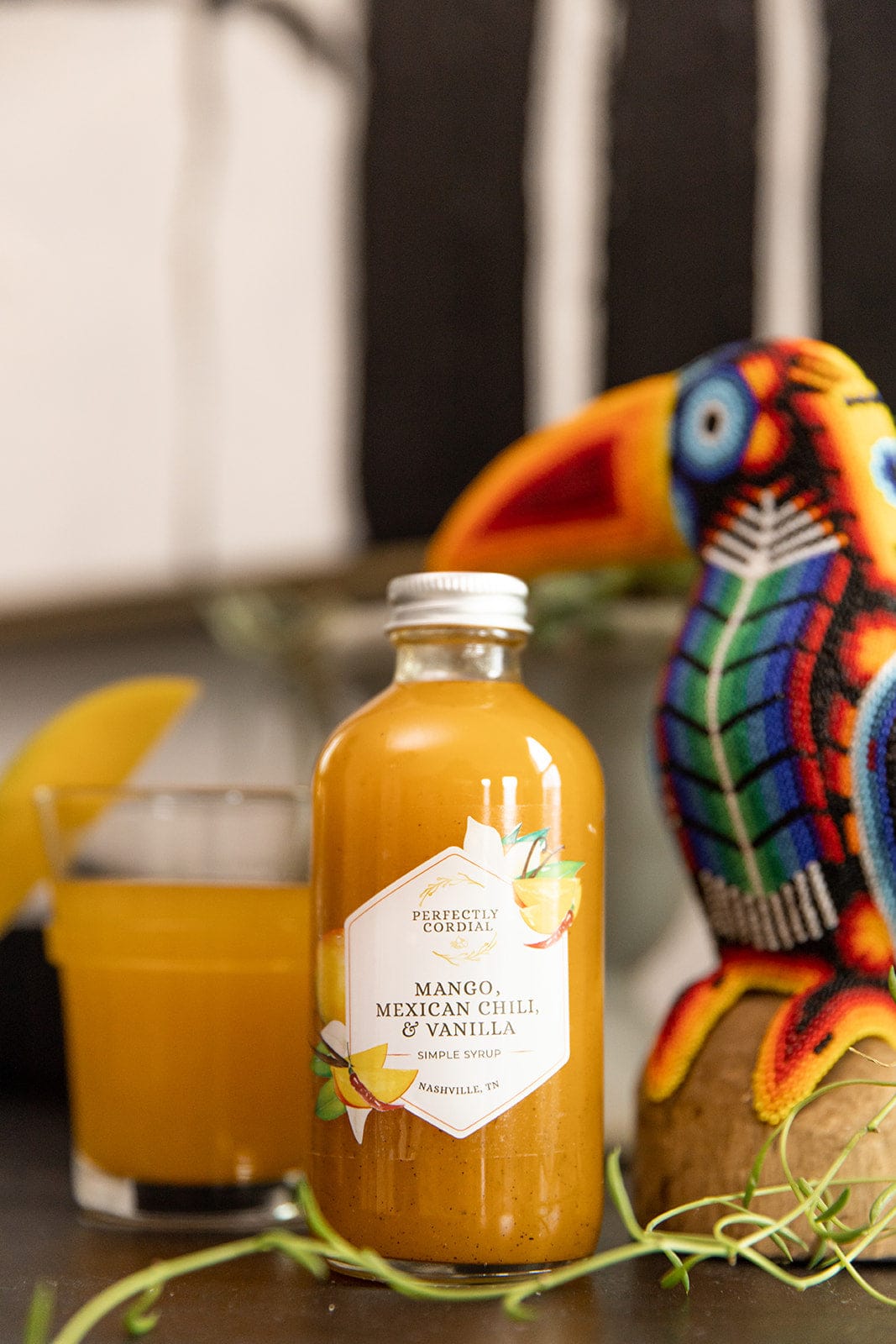 Mango Mexican Chili and Vanilla bottle beside a beaded toucan figure