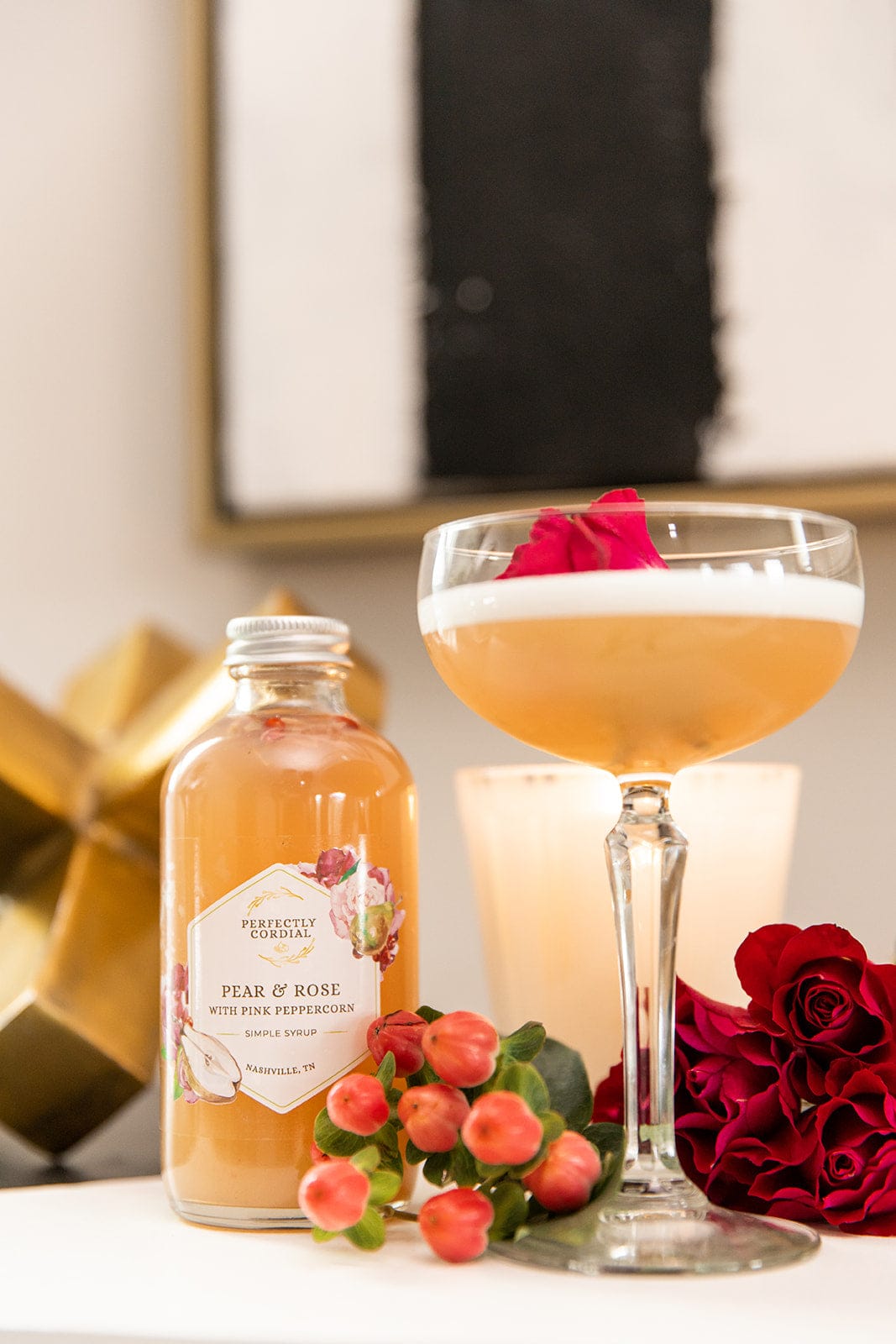 Pear Rose and Pink Peppercorn bottle beside a coupe cocktail garnished with a rose petal