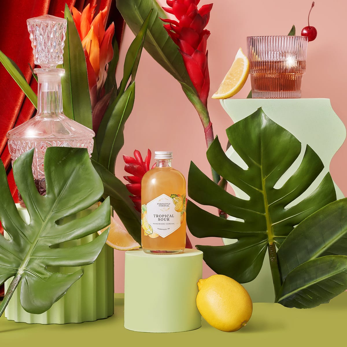 Tropical Sour cordial styled with monstera leaves, lemons and a crystal decanter